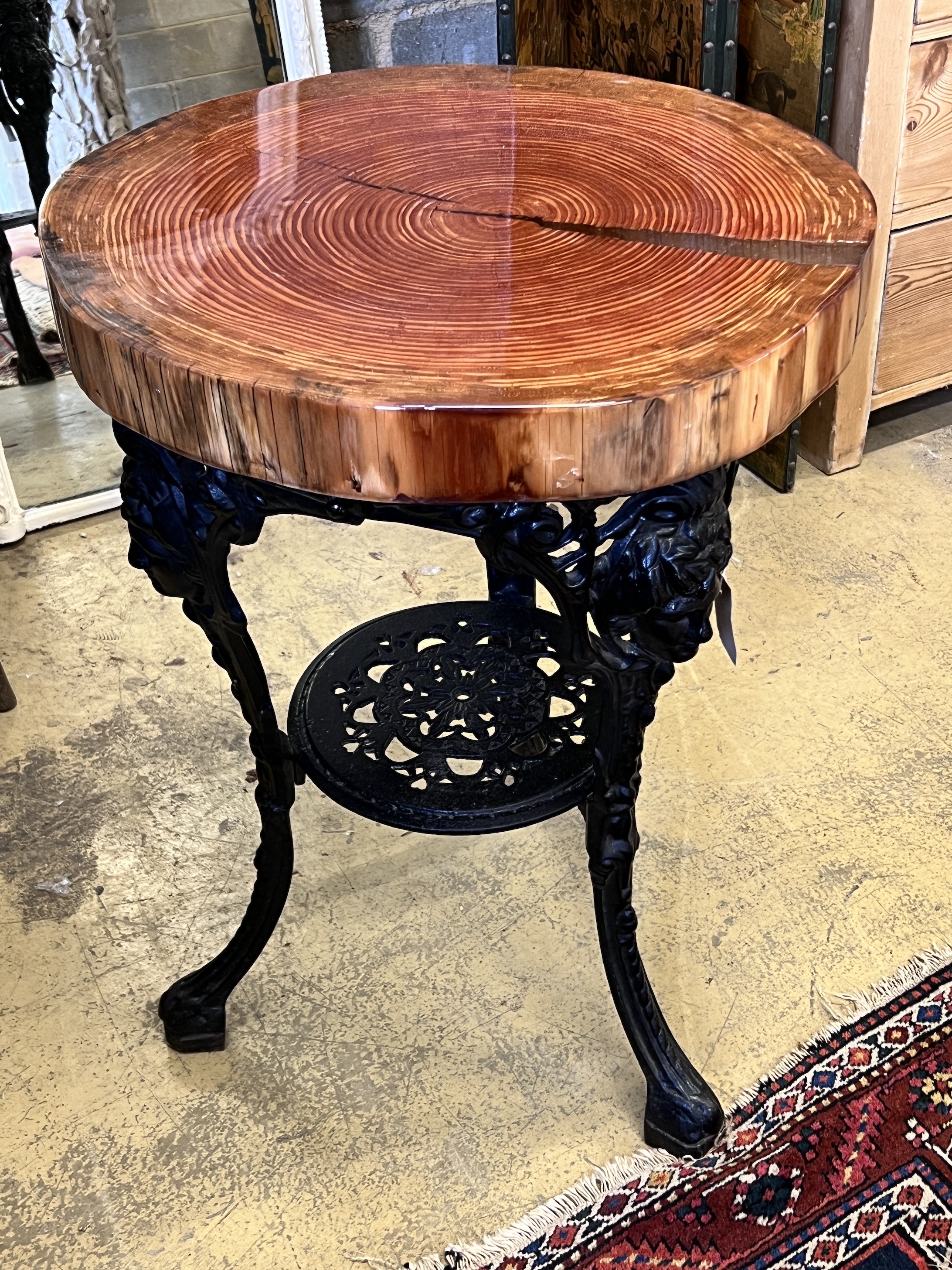 A resin encased cedar wood occasional table with cast iron underframe, diameter 53cm